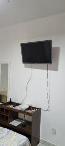 telewizor z płaskim ekranem wiszący na białej ścianie w obiekcie SUÍTE Princípio w mieście Vila Velha