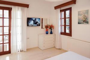 a bedroom with white walls and a dresser and windows at Villa Sea View Gem Steps to Zia Square Hot Tub in Lagoúdi Zía