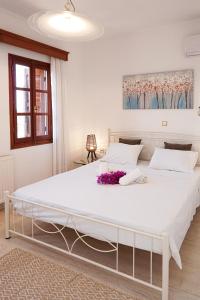 a bedroom with a large white bed with flowers on it at Villa Sea View Gem Steps to Zia Square Hot Tub in Lagoúdi Zía