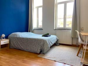 - une chambre avec un lit et un mur bleu dans l'établissement Maison Cosy 6 chambres 2 SDB toute commodité, à Roubaix
