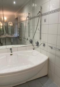 La salle de bains blanche est pourvue d'une baignoire et d'une douche. dans l'établissement Apartman De Lux, à Nyíregyháza