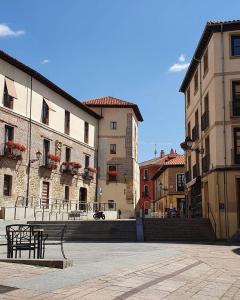 um banco no meio de uma cidade com edifícios em Bonito piso a 500m de la Catedral em León
