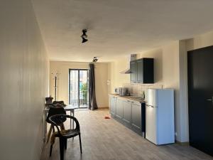 een keuken met een koelkast en een tafel met stoelen bij Gites les Voyageurs in Vogüé