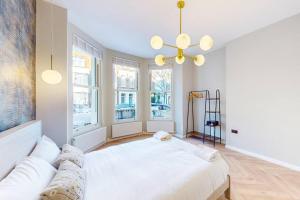 a bedroom with a large white bed and windows at Stunning 3BD flat in Kilburn with an outdoor area in London