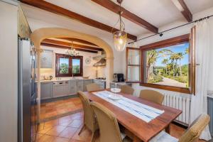 a kitchen and dining room with a wooden table and chairs at Villa Can Nofre, con un magnífico jardín y espectacular piscina in Capdepera