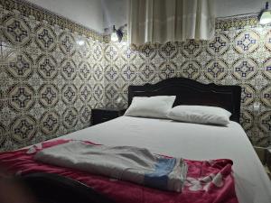 a bedroom with a white bed with a red blanket at Dar Ba sidi in Rabat