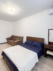 a bedroom with a bed and a couch at Апартаменты рядом с метро Раимбек in Almaty