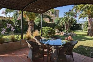 Un patio con mesa y sillas y palmeras. en Casita de la Higuera, en Jávea