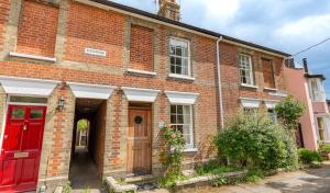 ein rotes Backsteingebäude mit einer roten Tür in der Unterkunft Palmer's Cottage in Southwold