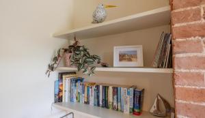 a book shelf with a bird sitting on top of it at Palmer's Cottage in Southwold