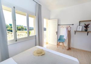 a white bedroom with a bed and a blue chair at Maxcaly Playa in Águilas