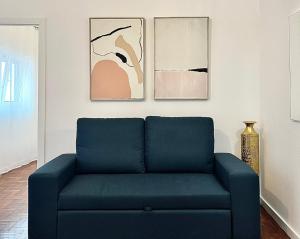 um sofá azul numa sala de estar com pinturas em Cantinho do Castelo em Brangança