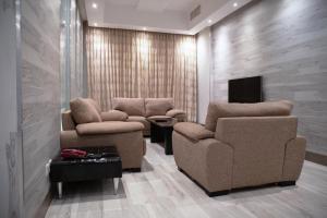 a living room with two chairs and a tv at Terrace Furnished Apartments Fintas 2 in Kuwait