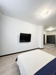a white room with a bed and a flat screen tv at Апартаменты рядом с метро Раимбек in Almaty