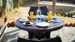 a wooden table with plates of food and a bottle of beer at Royal Adventures in Kodaikānāl