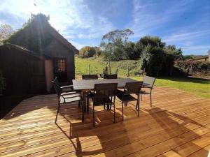 Una terraza de madera con una mesa y sillas. en Maison l'Escale du port, en Berville-sur-Mer