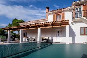 une villa avec une piscine en face d'une maison dans l'établissement Mallorca - Can Picafort - Finca Dos Amigos, à Muro