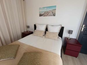 1 dormitorio con 1 cama blanca grande y 2 mesitas de noche en Maison l'Escale du port, en Berville-sur-Mer