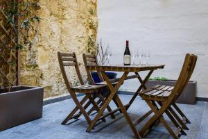 a wooden table with two chairs and a bottle of wine at Valletta collection - Mint Suite in Valletta