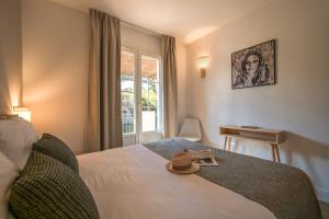 una camera da letto con un letto con un cappello sopra di St Tropez et plage à pied Escale de Charme - 3 a Saint-Tropez Altre 23 foto