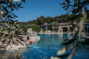 una mujer sentada en una piscina en un resort en Aquapetra Resort & Spa, en Telese Terme