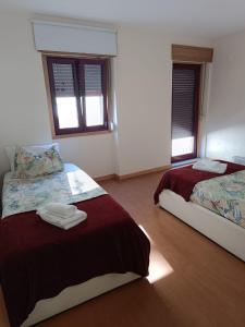 a bedroom with two beds and two windows at Casinha Miradouro in Vila Nova de Gaia