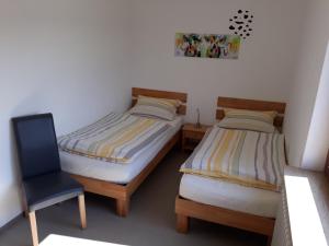 two twin beds in a room with a chair at Monteurwohnung Ferienhof Arold in Creglingen