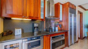 a kitchen with wooden cabinets and stainless steel appliances at Ko Olina Beach Villas B410 in Kapolei
