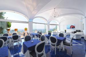 Hotel Villa Maria Pia في برايانو: غرفة بها طاولات وكراسي ونوافذ زرقاء
