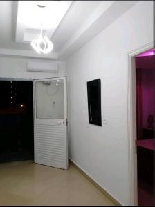een witte kamer met een televisie en een witte muur bij Sunset apartment in Kelibia