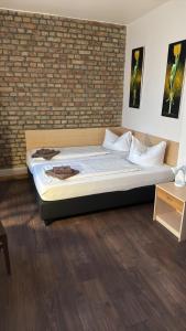 a bed in a room with a brick wall at Pensionszimmer Unicat in Potsdam