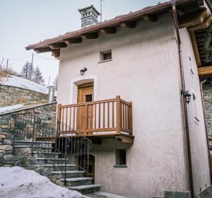uma casa com uma varanda de madeira ao lado em Lo Mieton - Affitti Brevi Italia em Champoluc