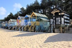 a row of colorful beach huts on the beach at Newgate Boathouse in Wells next the Sea