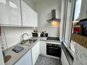 uma pequena cozinha branca com um lavatório e um micro-ondas em Le cocon des cloutiers - Central & Moyen séjour em Liège