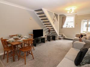 a living room with a table and a staircase at Foxglove Cottage in Richmond