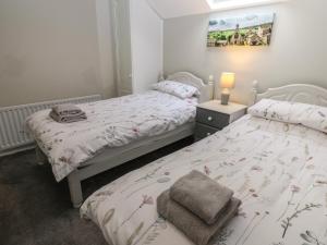 a bedroom with two beds and a lamp on a table at Foxglove Cottage in Richmond