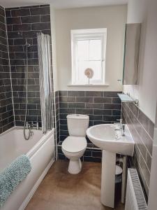a bathroom with a toilet and a sink and a tub at Dunes Walk Cottage in Camber