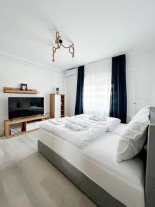 um quarto branco com uma cama grande e uma televisão em Ligeti Bástya Vendégház 