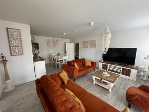 een woonkamer met 2 banken en een tv bij TOP appartement met garage "Au Franelle" in Oostende