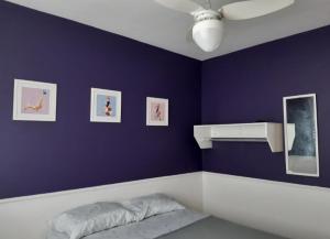 una camera da letto con parete viola, letto e ventilatore di Serra Mar Suítes,Lofts, e casas à 300 metros das praias ad Arraial do Cabo