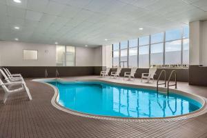 uma grande piscina num quarto de hospital com cadeiras em Ramada By Wyndham Niagara Falls near the Falls em Cataratas do Niágara