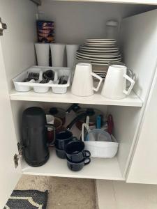 a cupboard filled with dishes and cups and plates at Casa de Vó in Campina Grande
