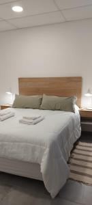 a bedroom with a large white bed with a wooden headboard at Apart Hotel Concepcion in Concepción