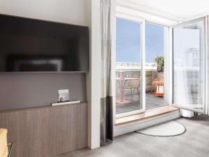 a living room with a flat screen tv and a balcony at Novotel Paris Gare De Lyon in Paris