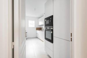 3 bedroom flat close Montmartre في باريس: مطبخ أبيض مع موقد وميكروويف