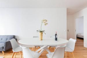 3 bedroom flat close Montmartre في باريس: غرفة طعام بيضاء مع طاولة بيضاء وكراسي بيضاء