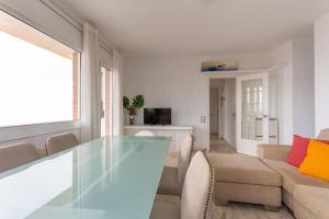 - un salon avec une table en verre et un canapé dans l'établissement Luminoso apartamento frente al mar, à Castelldefels