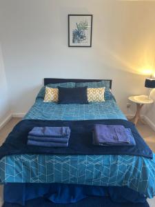 Una cama azul con sábanas y almohadas azules. en KB51 Charming 2 bed house in Horsham, pets very welcome and long stays with easy access to London, Brighton and Gatwick, en Warnham