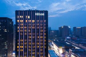 ein hohes Gebäude mit einem Schild auf dem Hügel in einer Stadt in der Unterkunft Hilton Nanjing in Nanjing
