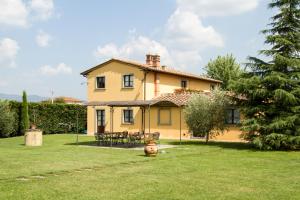 ein großes gelbes Haus in einem Hof mit Gras in der Unterkunft Il Giardino Degli Ulivi in Cortona